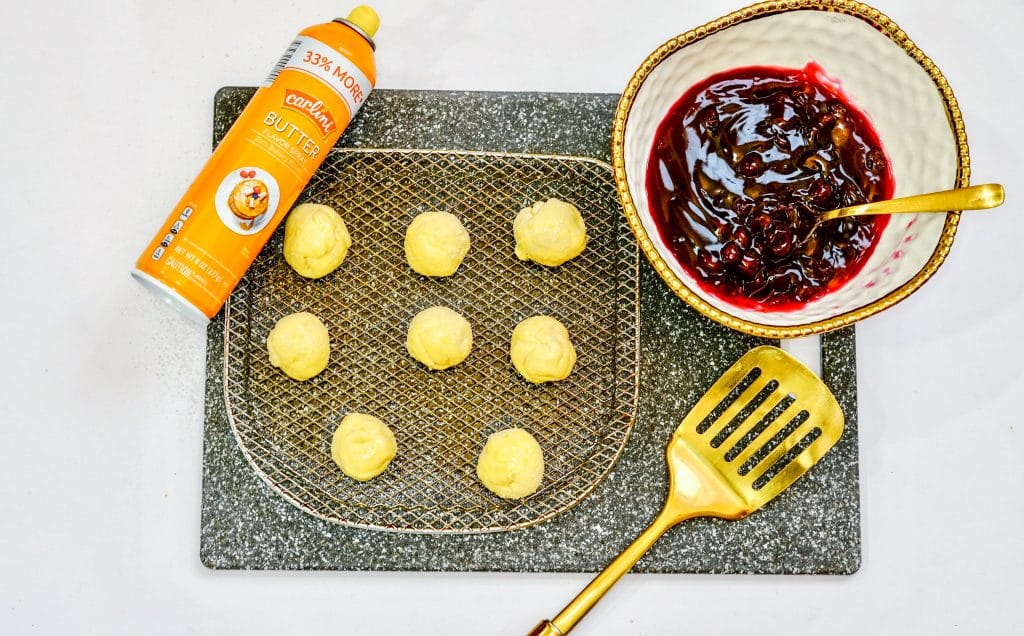 Crescent Roll Balls Sprayed with Cooking Spray. Step Three of Air Fryer Blueberry Dessert Recipe that is made with crescent rolls, blueberry pie filling, cooking spray and powdered sugar.